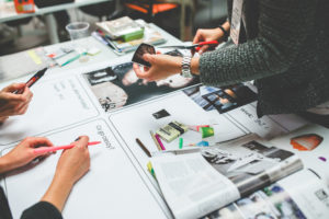 Building your brand by finding the right niche for your web design business - people's hands reviewing print marketing materials